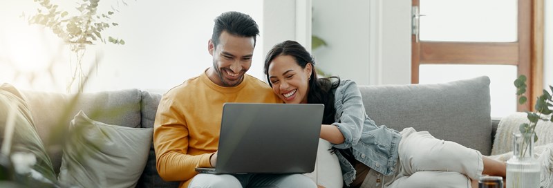 couple sitting on couch with laptop